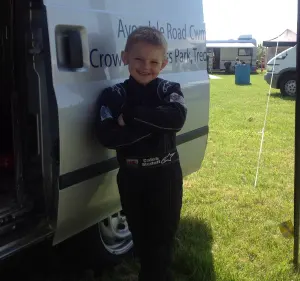 Caleb McDuff posing with Team BRIT racing helmet and car