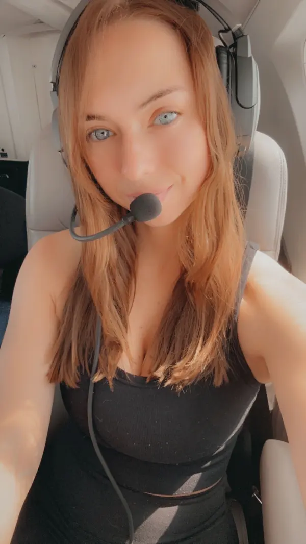 Becca Aviatrix posing in a pilot uniform with a confident smile, representing her aviation lifestyle brand