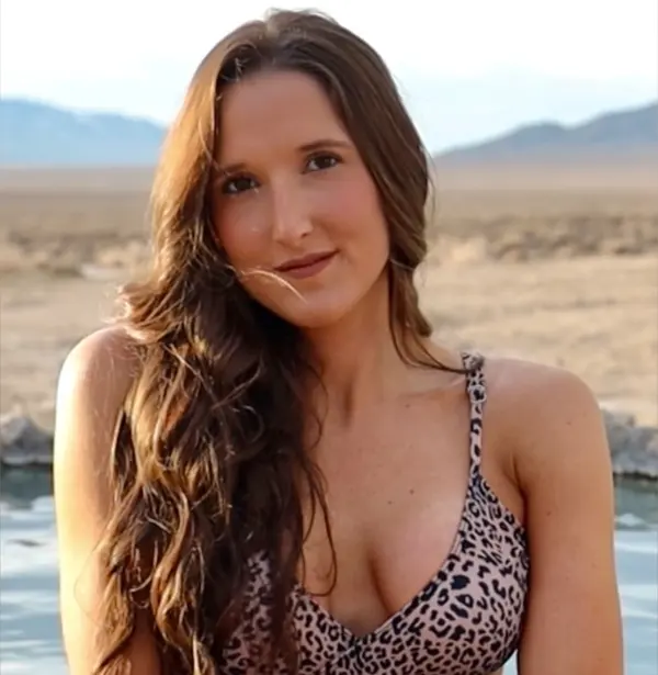Hannah Camps posing near her truck camper during an outdoor adventure